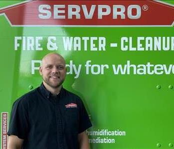 Male project manager smiling in front of SERVPRO truck 